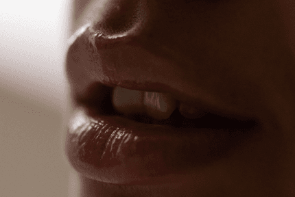 Close-up of a woman’s slightly parted lips in warm, subtle tones.